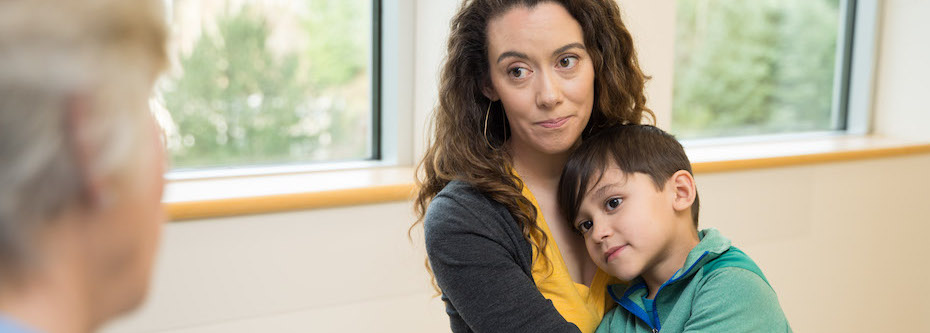Photo of an adult sitting with a child in a hospital waiting room