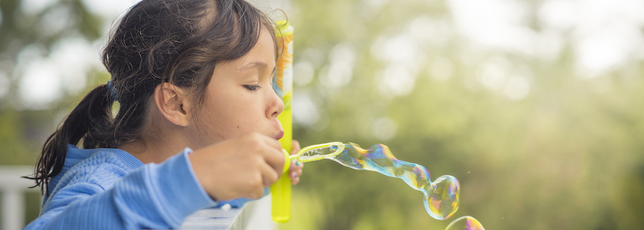Photo of a child blowing bubble outside