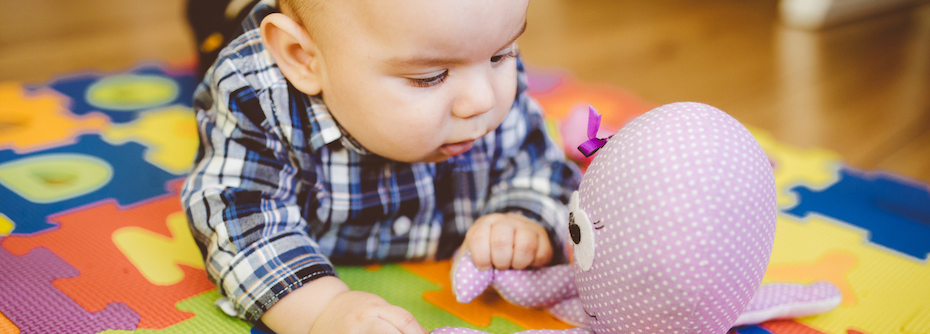 Photo of a baby playing with toys on the floor