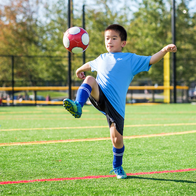 Photo of a child kicking a ball into the air