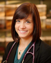 Portrait of brunette woman smiling, with a stethoscope draped on her shoulders