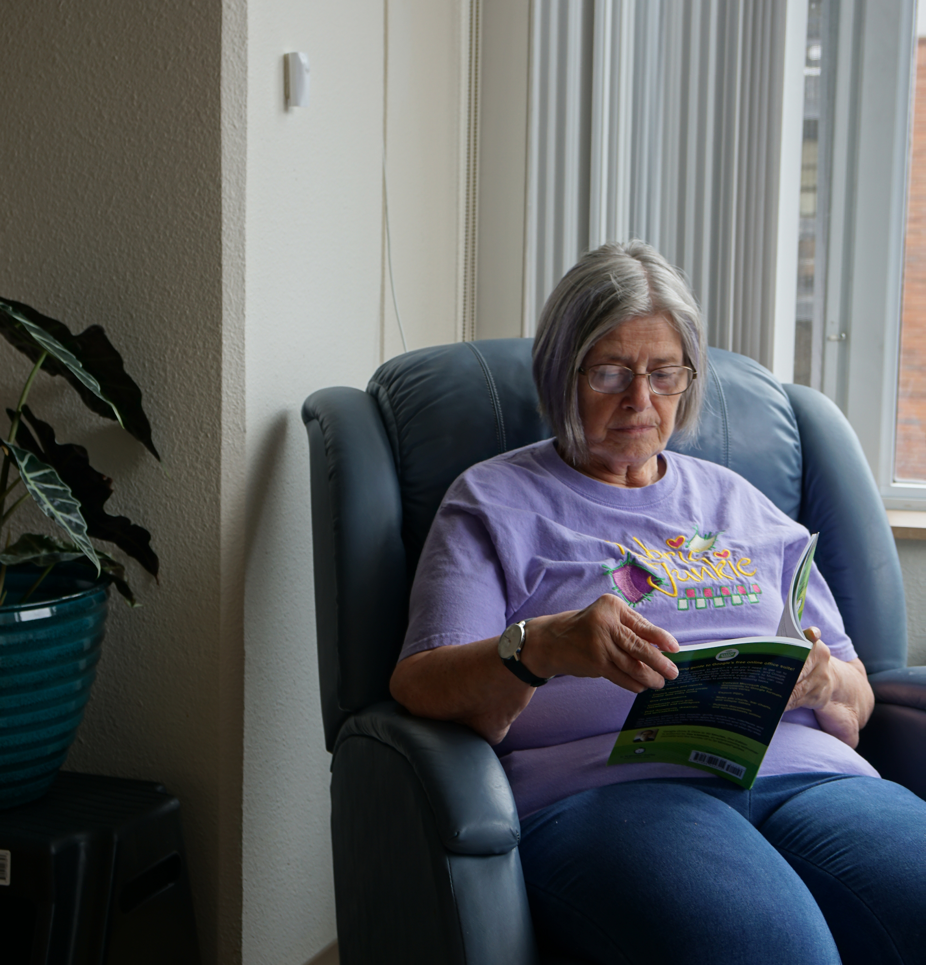 Research participant sits on an armchair reading a book in a living room