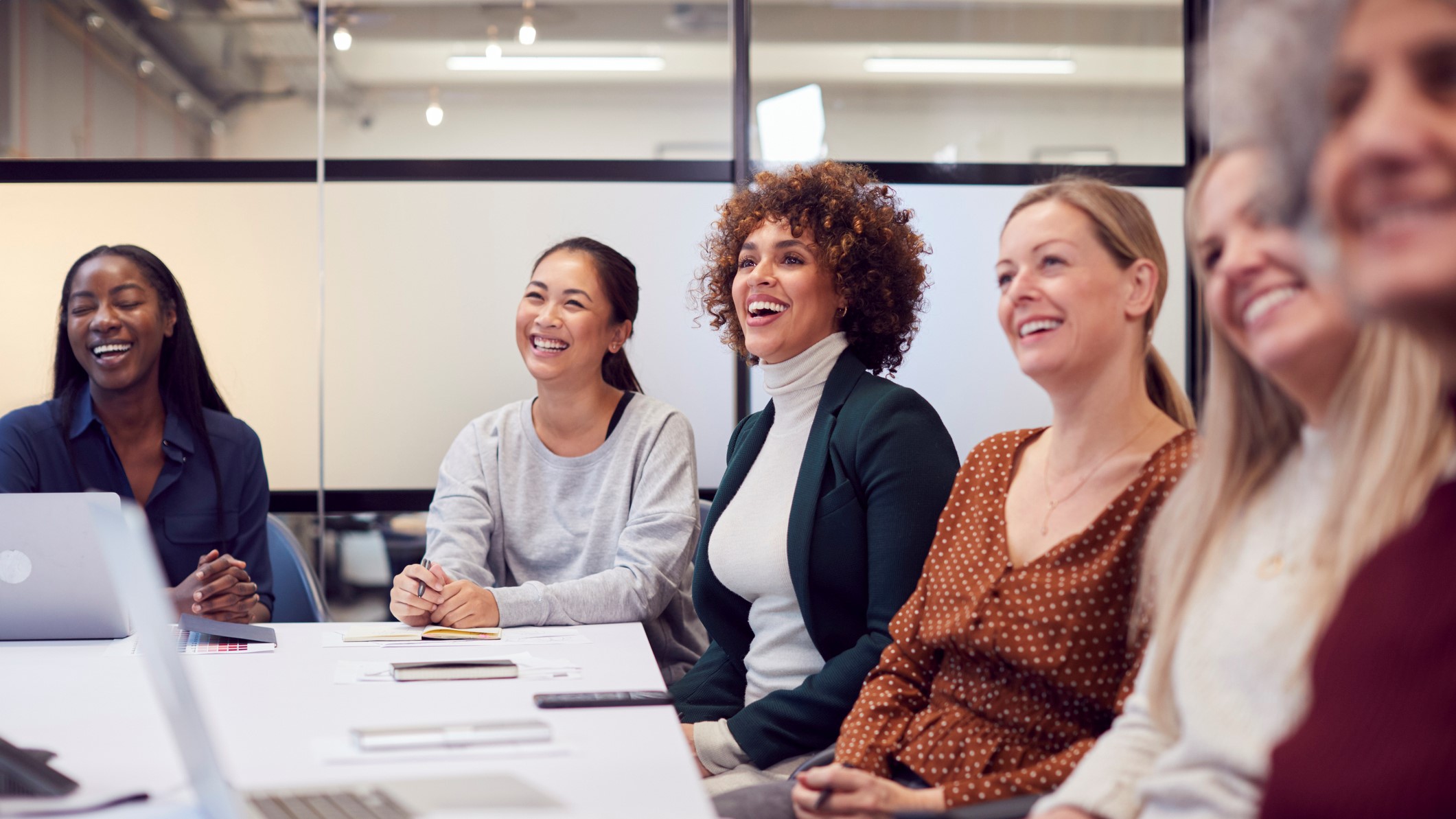 group of women sits around table, talking and smiling