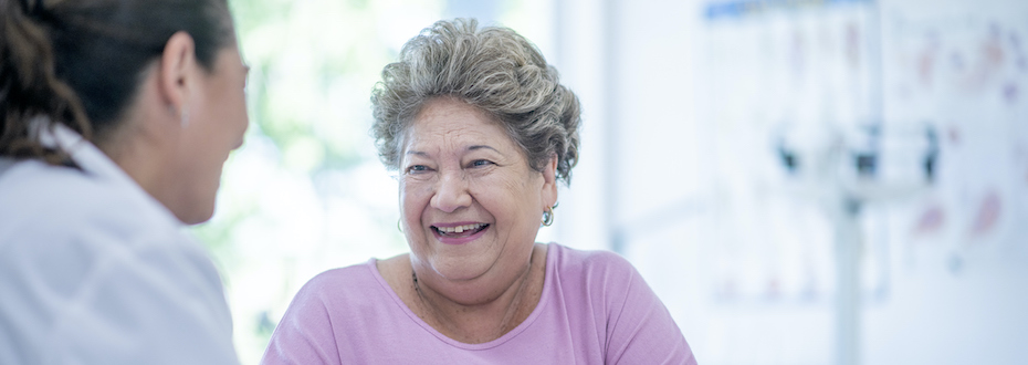 Stock photo of a person with short hair and a pink shirt smiling at a healthcare provider