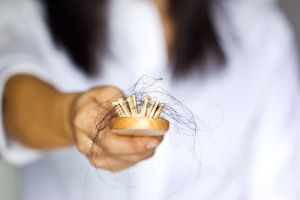 Woman holding brush with many strands of hair