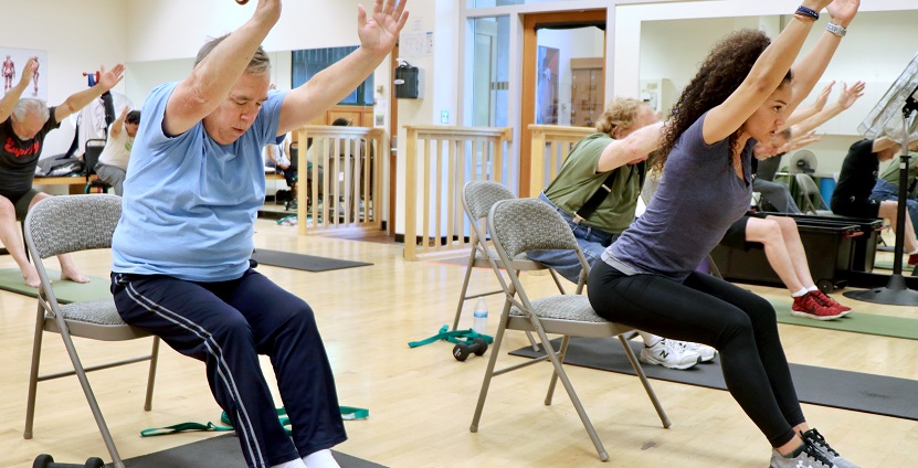 People doing chair exercises with a trainer. 