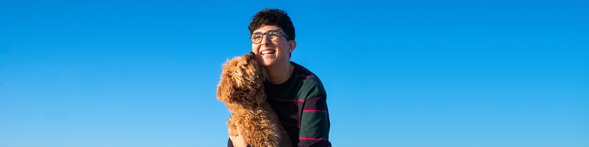 Photo of a person and a dog in front of a blue sky