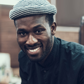 A man wearing a beanie smiling at the camera