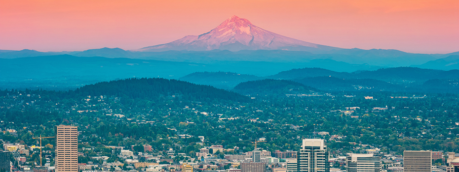 A stock photo of Mt. Hood and Portland, OR at sunrise with a pink sky.
