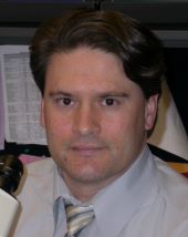 male scientist with brown hair, in white shirt and tie