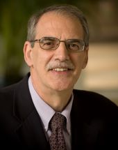 Professor with glasses and mustache, in a suit and tie