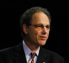 man with short brown hair and glasses, in a suit and tie