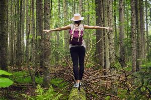 Woman balances on a log in the forest