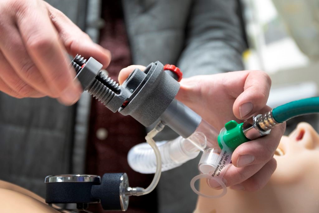 A technician works with a 3d printed ventilator on a test mannequin.