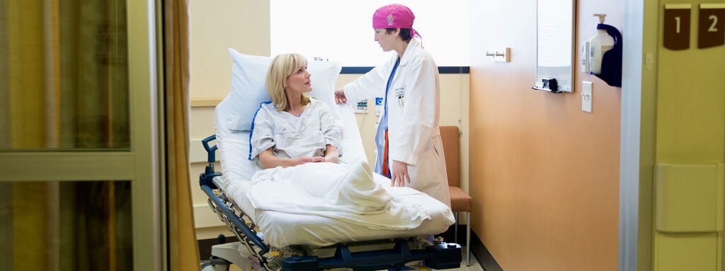 A doctor reassures a breast cancer patient in a hospital room.