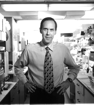 Black-and-white photo of Dr. Brian Druker standing in a research lab