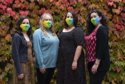 Oregon Clinical and Translational Research Institute Navigator Researcher Support Team posing in front of a tree with fall colors and wearing masks.