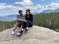 A man and a woman sitting on rock reading a map in the mountains.