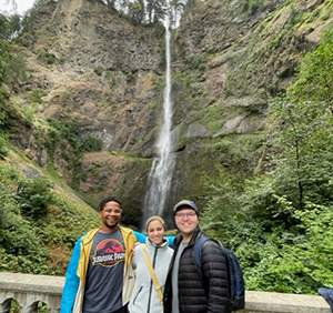 Three residents pose in front of waterfalls outside Portland.