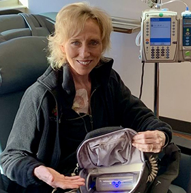 A woman sitting in a chair smiling in a hospital chair while receiving Electric field therapy.