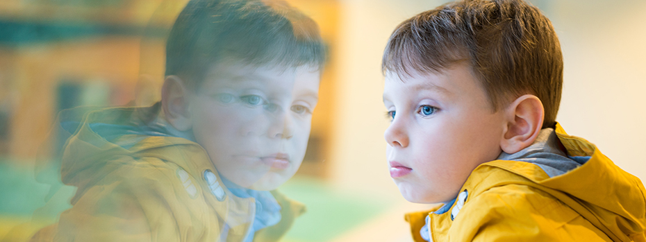 A child calmly looks through a window in a colorful waiting area at Doernbecher Children’s Hospital.