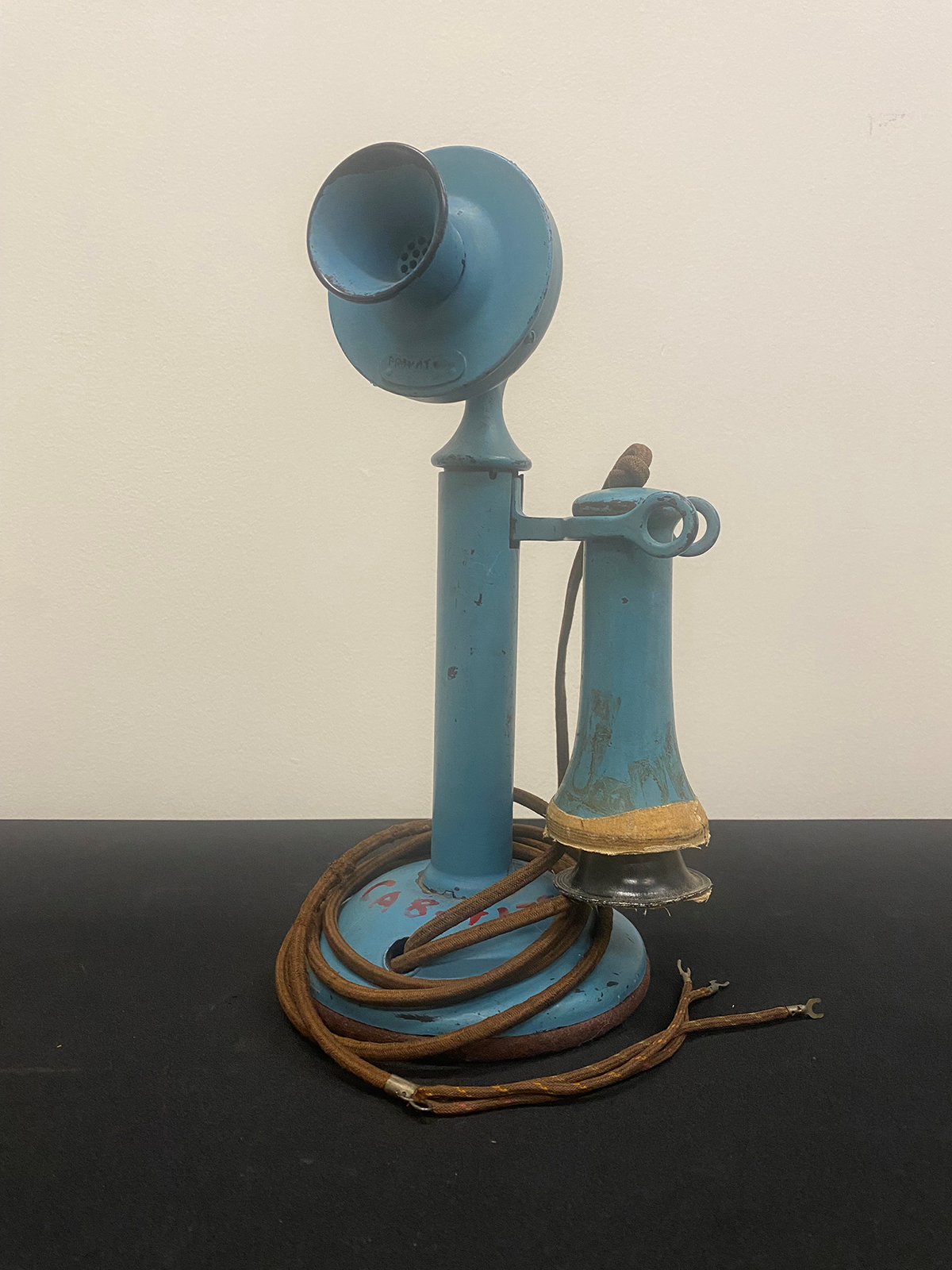 Color photograph of blue, old-fashioned candlestick style telephone