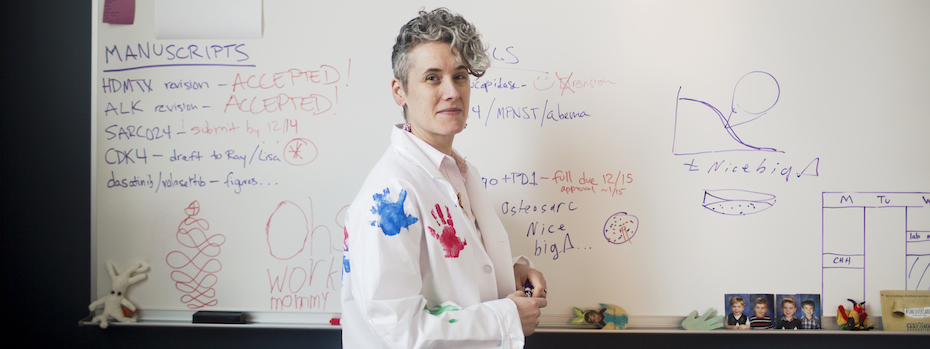 Oncologist Dr. Lara Davis stands in front of a whiteboard in her lab.