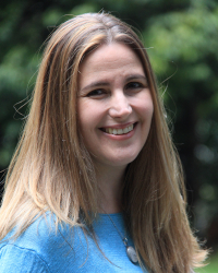 Photographic portrait of Heather Schiffke looking at camera wearing a blue sweater