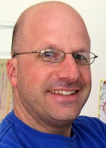 Image of Adam King with glasses and blue t-shirt