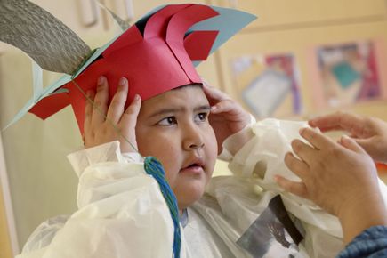 A young boy wearing a paper graduation hat.