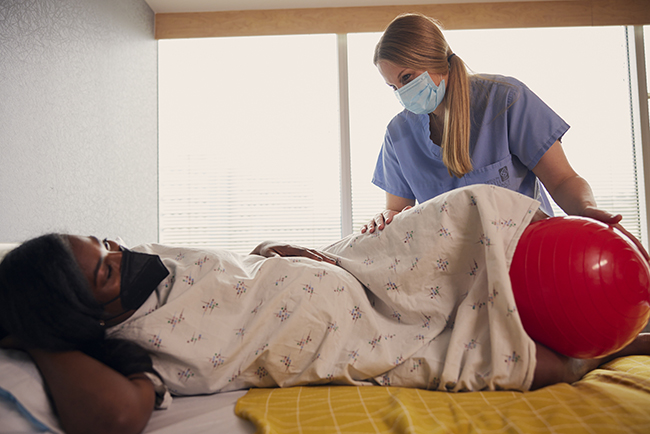 Nurse-midwife Bridget Lee helps her patient use a supportive birthing ball during labor.