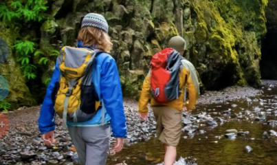 A man and a woman backpacking through a river gorge.