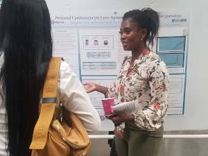 Raiyasha describes her research poster to a visitor.