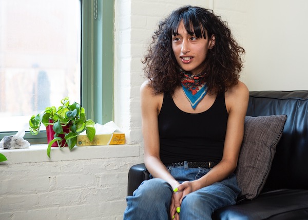 A smiling transgender woman sitting on a therapist's couch.