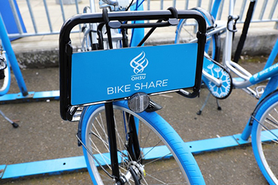 A sign on a bicycle in a bike corral identifies it as part of OHSU’s Bike Share program.]