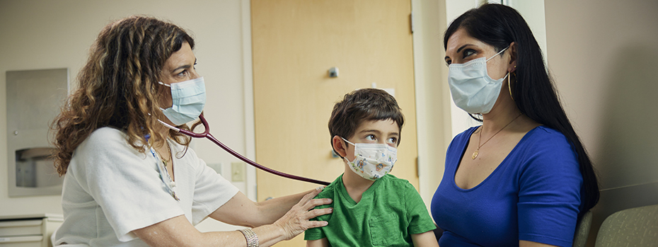 An OHSU Doernbecher nurse practitioner visits with a young patient and his parent.]