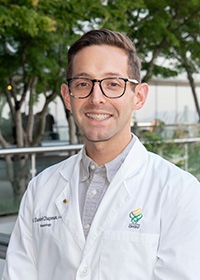 Daniel Chapman, M.D., MS fellow, posed smiling in his white coat