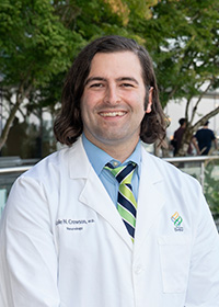 Cole Crowson, M.D., MS fellow, posed and smiling in his white coat