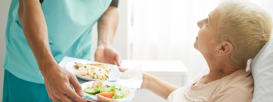A hospital patient receives a healthy meal delivered by a meal assistant.