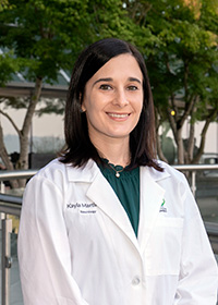 Kayla Martin, M.D., MS fellow, posed and smiling in her white coat