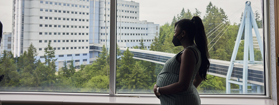 A pregnant person looks out the window in one of our spacious, comfortable suites at the OHSU Family Birthing Center.