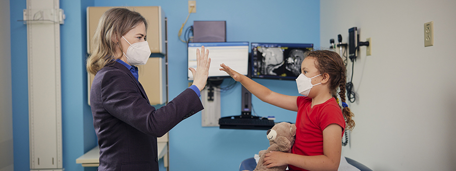 Dr. Collins, pediatric neurosurgeon, gives a young patient a high-five.