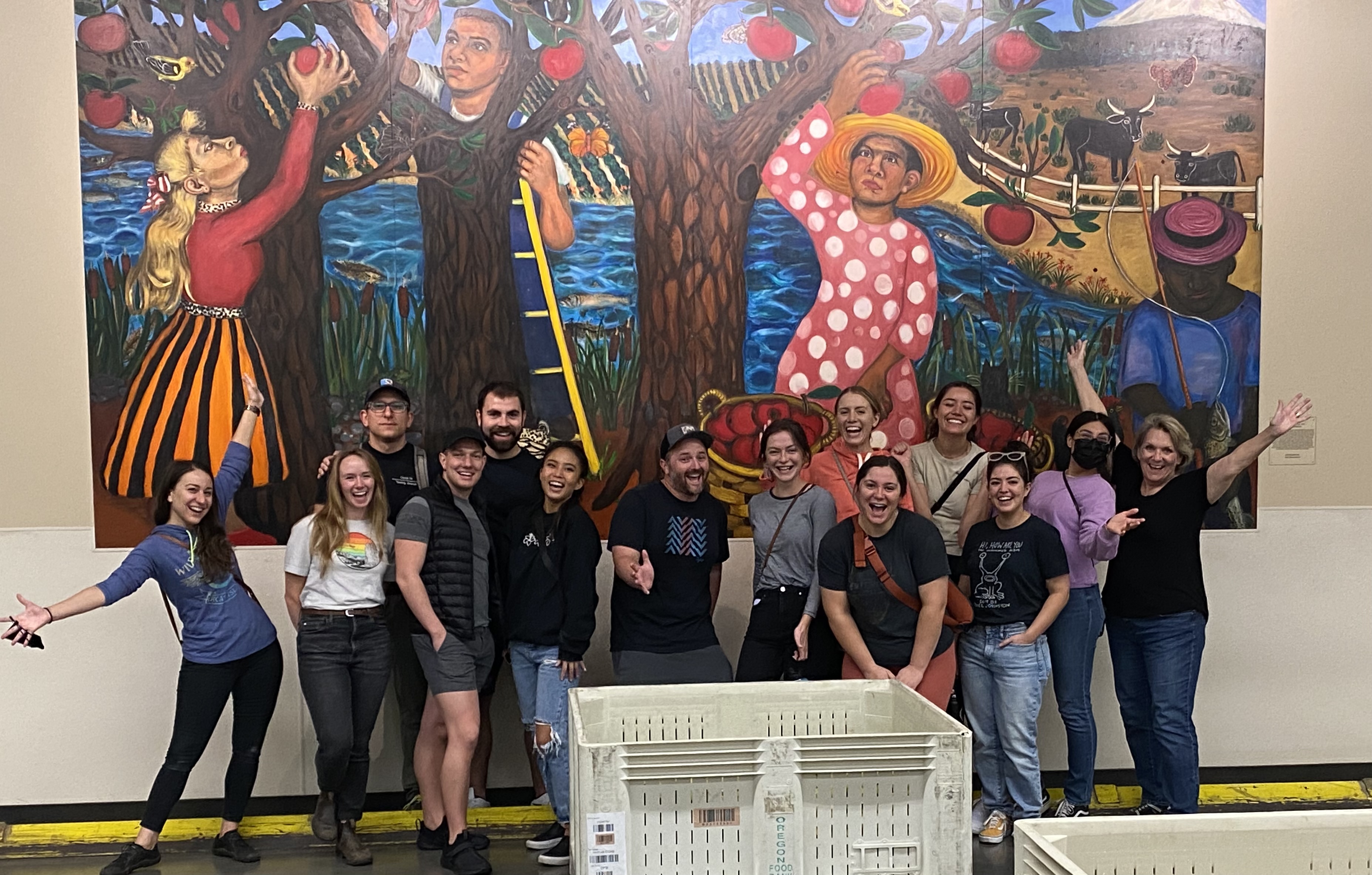 Students and faculty posing in front of a colorful mural. 