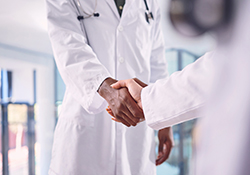 A close-up view of two doctors shaking hands.