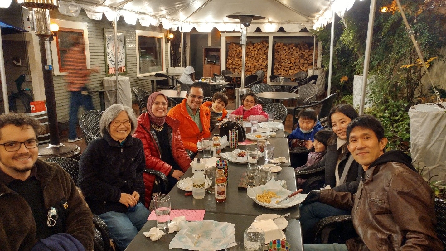 Members of Shyng lab gathered around an outdoor dining table at a restaurant, smiling at the camera.