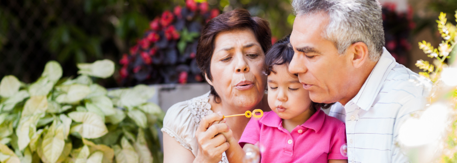 Smiling couple with child blowing bubbles. 