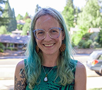 Valerie R. Osterberg outdoors and smiling, with terrific, gradient green hair
