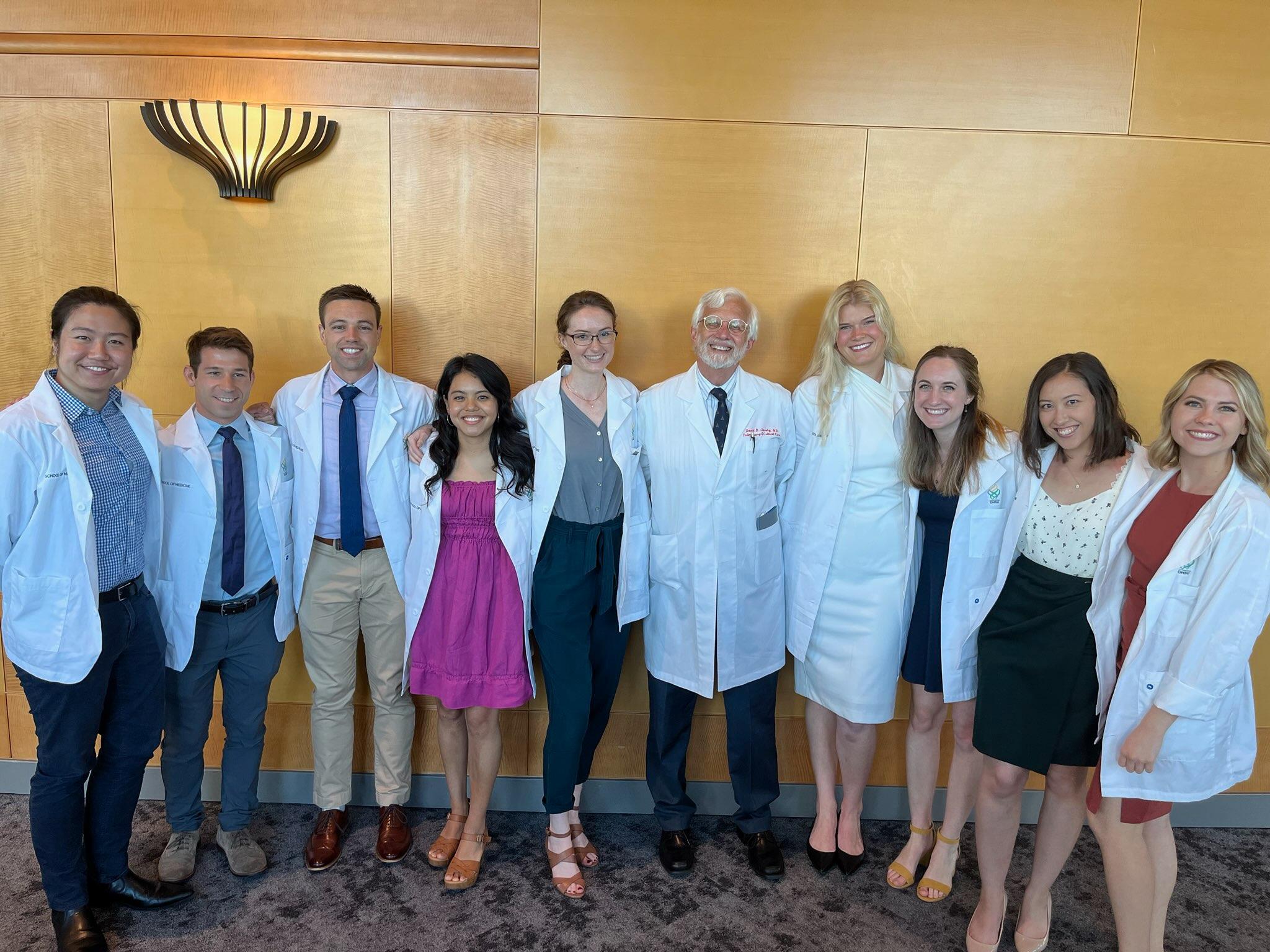 MD/PhD Program Director with 9 students in white coats
