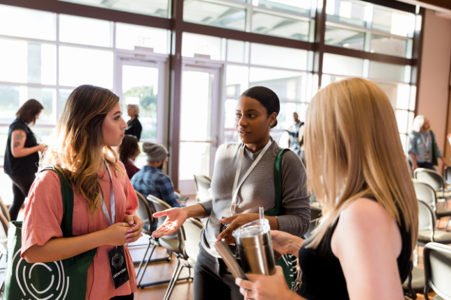 Three women talking at a conference.