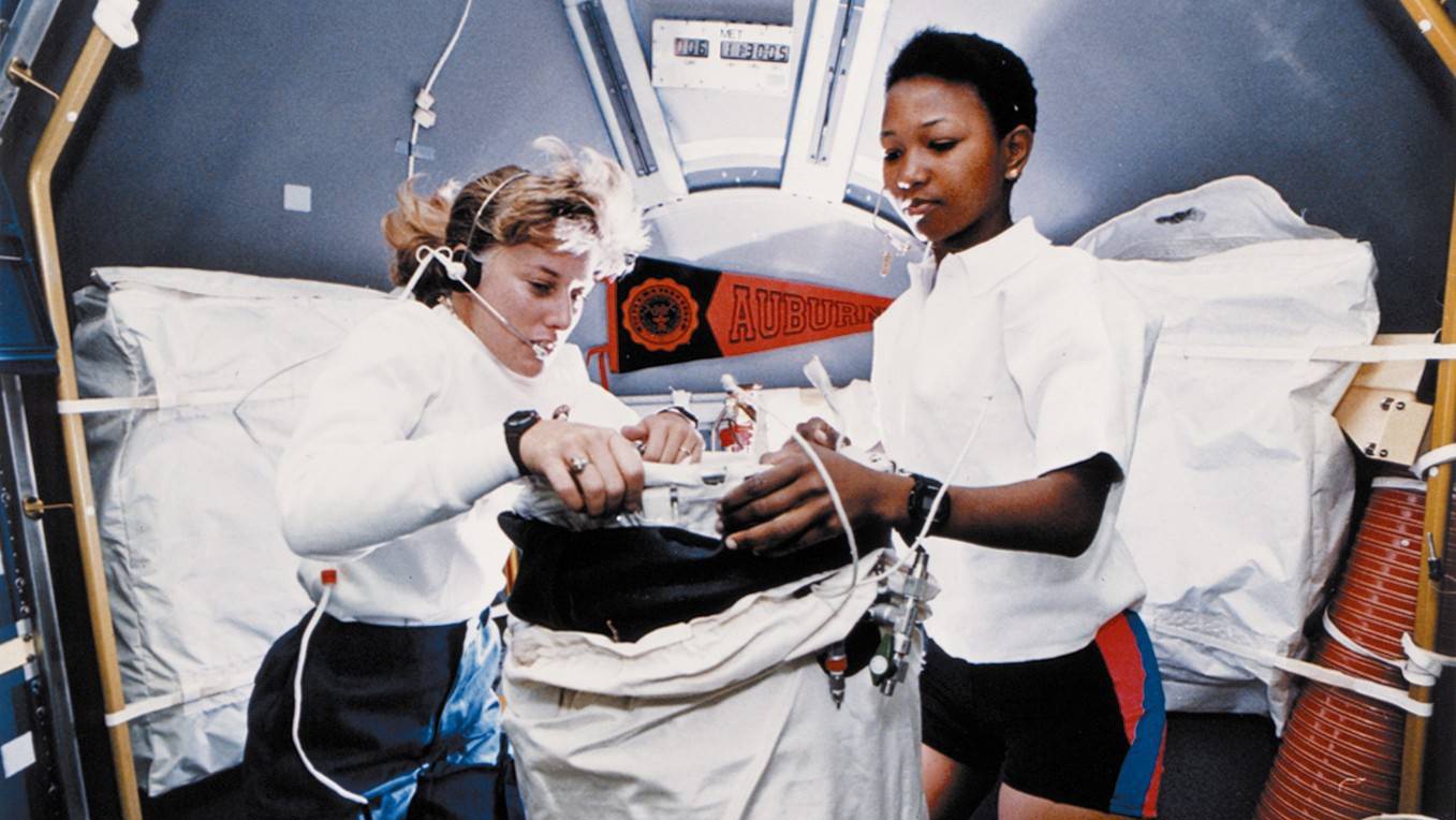 Mae Jameson and another astronaut work aboard a shuttle.